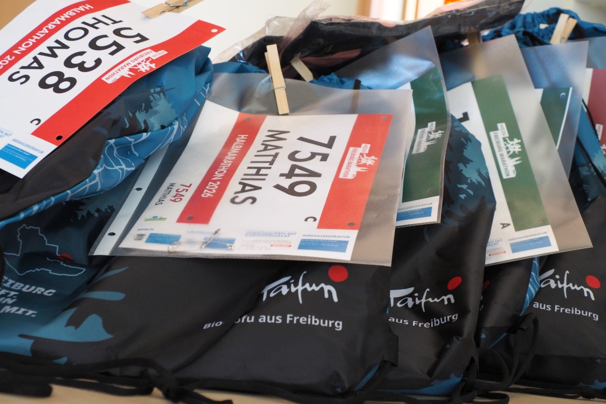 Mehrere Beutel mit Startunterlagen und -nummern stehen gerichtet nebeneinander.